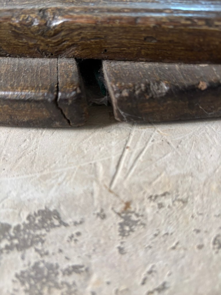 the wooden lid of the font and then stone with deep lines etched in it. 