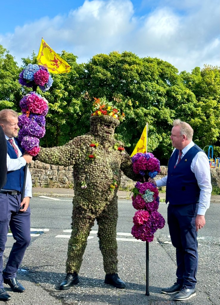 The burryman standing with his two attendants in the sunshine. 