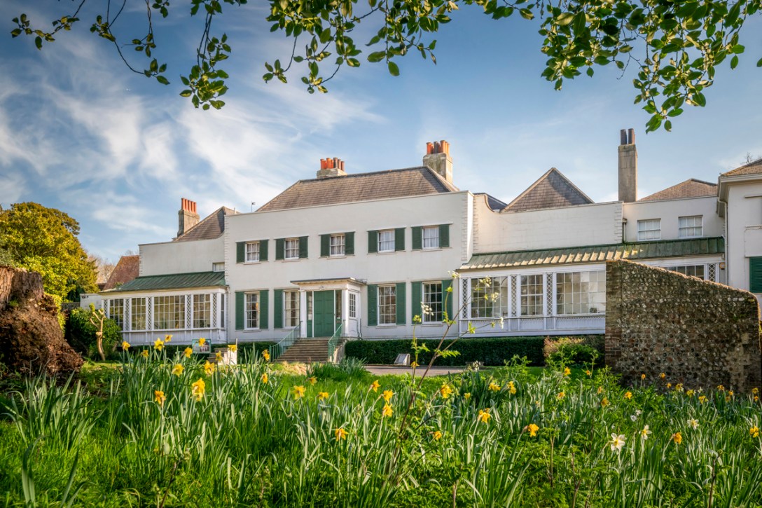 A grand white building against a blue sky with spring flowers in the foreground.