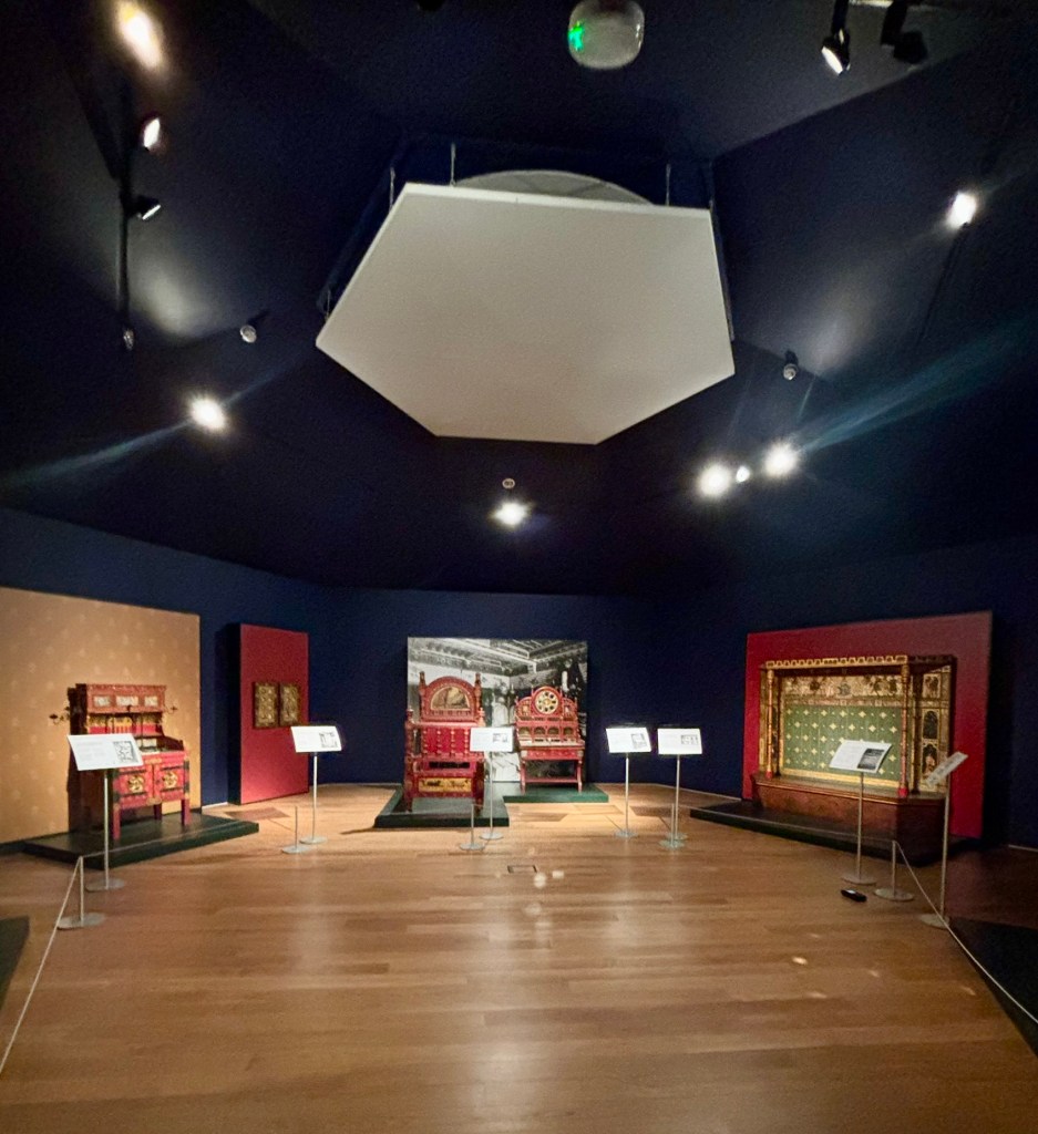 A large hexagonal room with deep blue walls and ceiling. In the room are pieces of red coloured furniture.