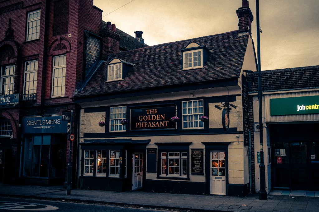 The Pheasant at night with lights glowing from inside and a stormy sky above, 
