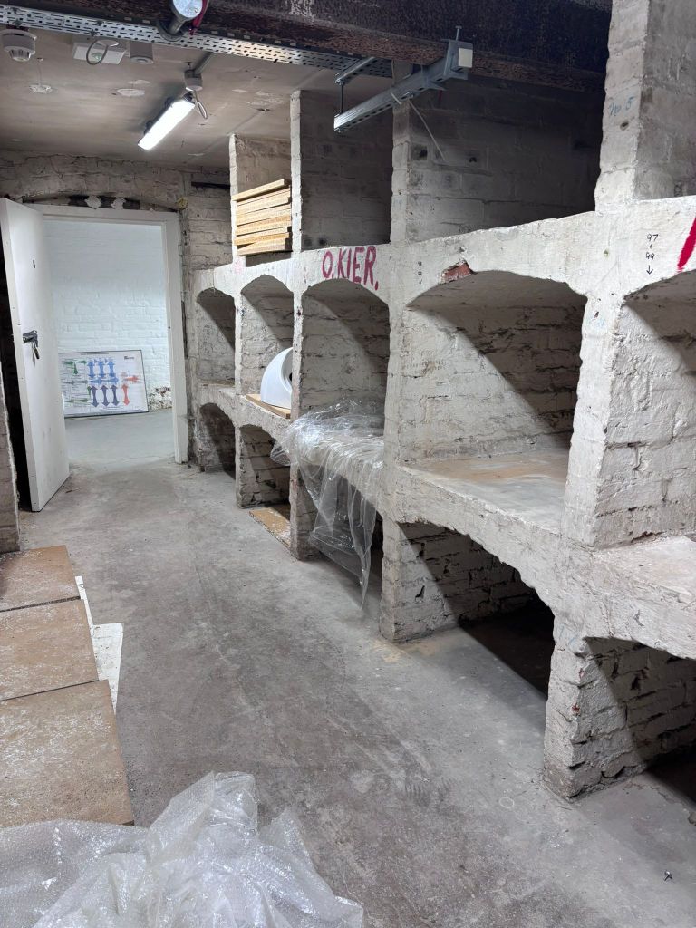 a cellar with whit washed shelves which once held wine bottles. 