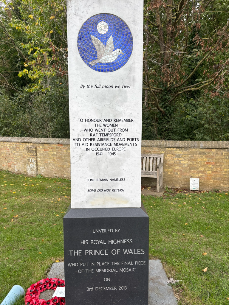 A marble monument with a mosaic of a white bird flying below moon in mother of pearl on a blue tile background. 
